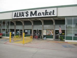 A grocery store building entrance with a sign that says "Alva's Market"